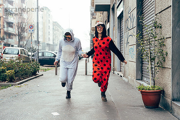 Frauen tragen Erwachsenen-Bodysuits und halten sich auf der Straße an den Händen