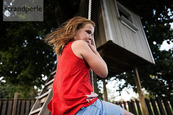 Mädchen schwingt am Seil unter einem Baumhaus