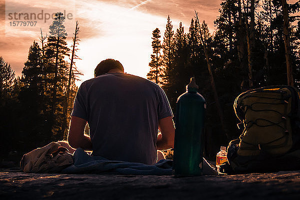 Junger männlicher Wanderer  der bei Sonnenuntergang eine Pause macht  Tuolumne Meadows  oberer Teil des Yosemite Nationalparks  Kalifornien  USA