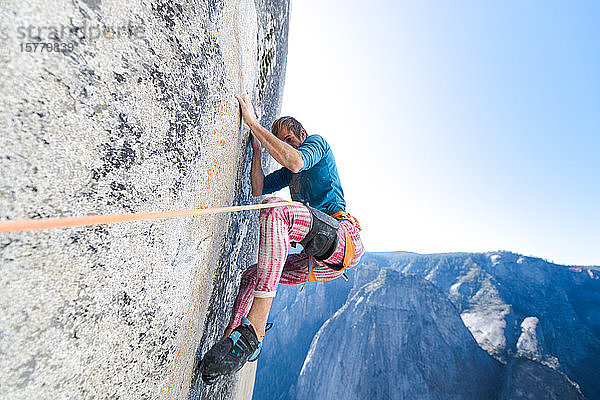 Tiefblick auf einen Bergsteiger  der die steile Wand von The Nose  El Capitan  Yosemite National Park hinaufklettert.