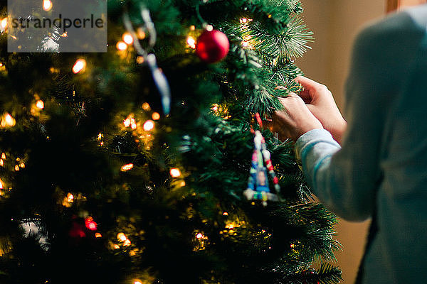 Person  die zu Hause den Weihnachtsbaum schmückt