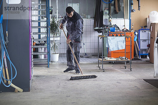 Arbeiter reinigt Boden in der Werkstatt