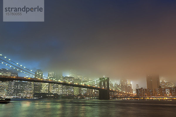 Die Skyline von Manhattan und die Brooklyn-Brücke im Nebel in der Abenddämmerung  New York City  USA