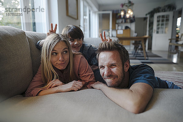 Glückliche Familie liegt auf dem Sofa  der Sohn macht sich über seine Eltern lustig