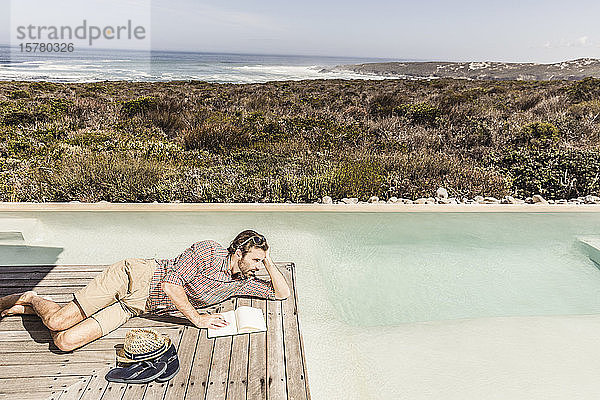 Mann neben einem Schwimmbecken mit einem Notebook