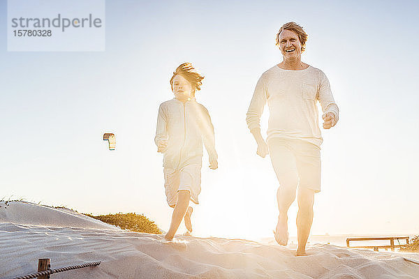 Vater amüsiert sich mit seinem Sohn am Strand  rennt im Sand