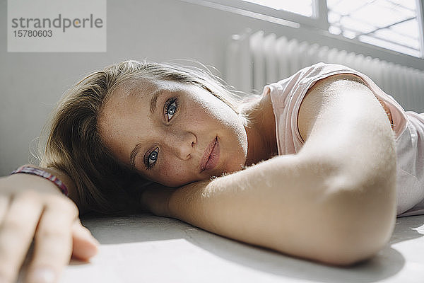 Porträt einer schönen blonden jungen Frau auf dem Boden liegend