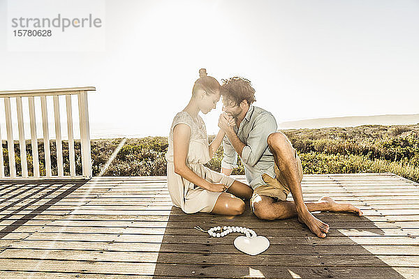 Zärtliches junges Paar sitzt im Sommer auf der Terrasse an der Küste