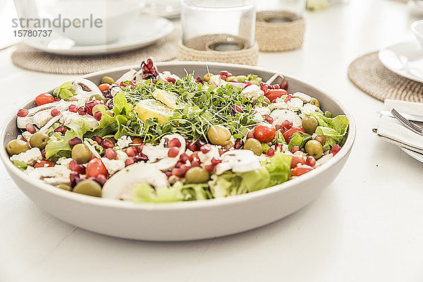Schale mit gemischtem Salat mit Granatapfelkernen auf gedecktem Tisch