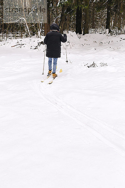 Rückenansicht einer Frau auf Skiern im Winterwald