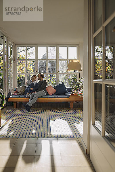 Zärtliches Paar entspannt sich zu Hause im Sonnenzimmer
