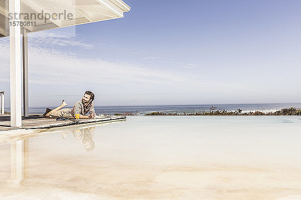 Mann liegt neben dem Pool eines Strandhauses