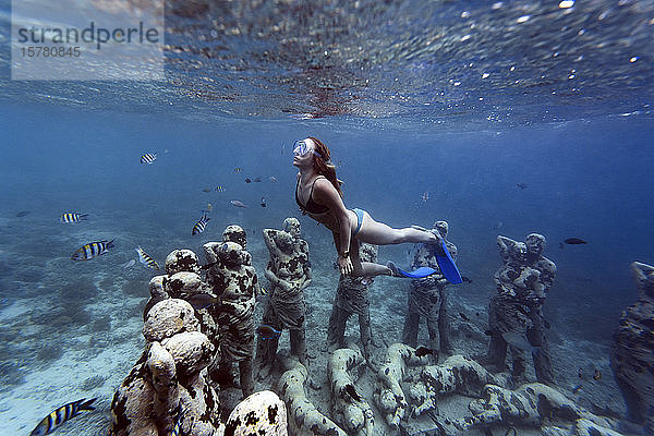 Frau schwimmt in der Nähe einer Unterwasser-Skulptur von Jason deCaires Taylor  Insel Gili Meno  Bali  Indonesien
