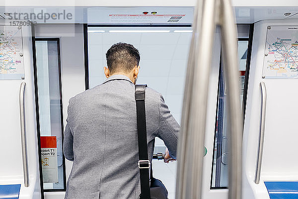 Rückansicht eines jungen Geschäftsmannes mit Elektroroller beim Verlassen der U-Bahn