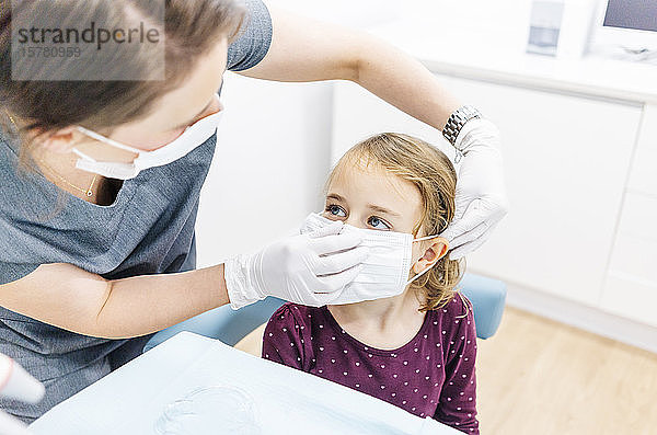 Mädchen beim Zahnarzt  das eine Maske erhält