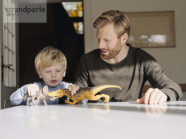 Vater und Sohn spielen zu Hause mit Dinosaurierfiguren