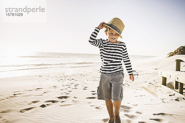 Porträt eines lächelnden Jungen mit Hut am Strand