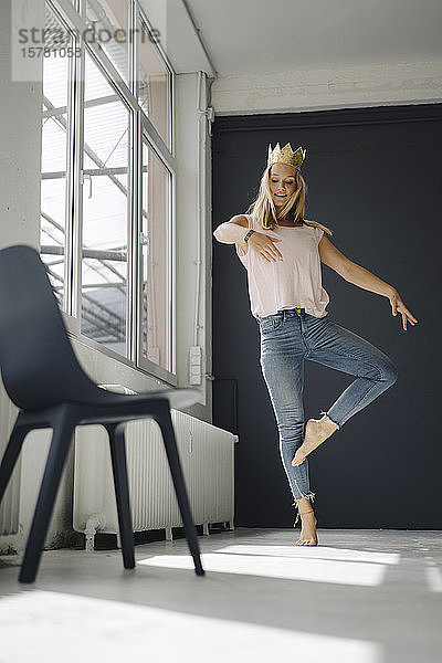 Blonde junge Frau mit tanzender Krone auf einem Dachboden