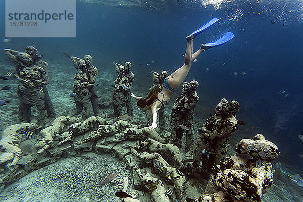 Frau schwimmt in der Nähe einer Unterwasser-Skulptur von Jason deCaires Taylor  Insel Gili Meno  Bali  Indonesien