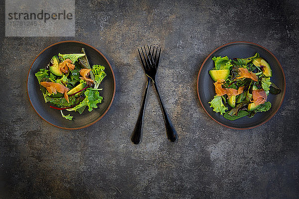 Teller grüner Salat mit Feldsalat  Rucola  Spinat  rotem Blattsalat  Rote-Bete-Blättern  Avocado  Lachsfleisch und Balsamico-Essig