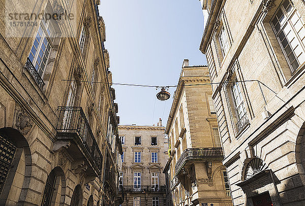 Frankreich  Gironde  Bordeaux  Niedrigwinkelansicht einer Straßenlaterne  die zwischen Altstadtwohngebäuden hängt