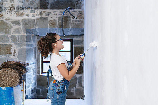 Mädchen malt eine Wand in einem Haus