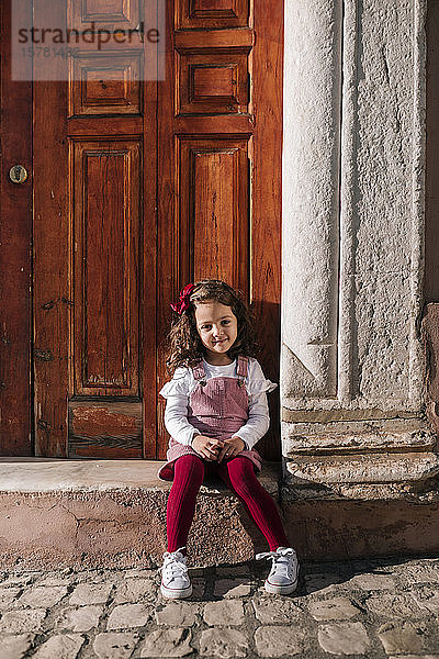 Porträt eines lächelnden Mädchens auf der Vordertreppe sitzend
