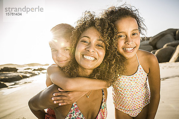 Porträt einer glücklichen Mutter mit ihren zwei Kindern  die sich am Strand amüsieren