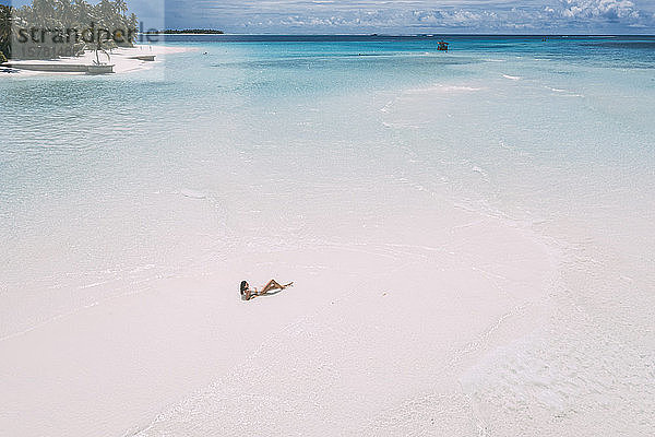 Frau liegt auf einer Sandbank im Meer  Insel Maguhdhuvaa  Gaafu-Dhaalu-Atoll  Malediven