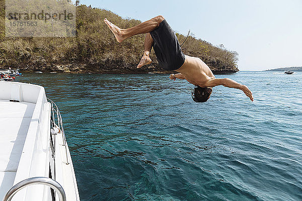 Junger Mann springt aus einem Boot  Insel Lembongan  Bali  Indonesien