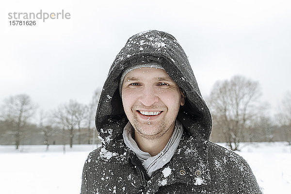 Porträt eines glücklichen Mannes in Winterlandschaft mit Schneefall