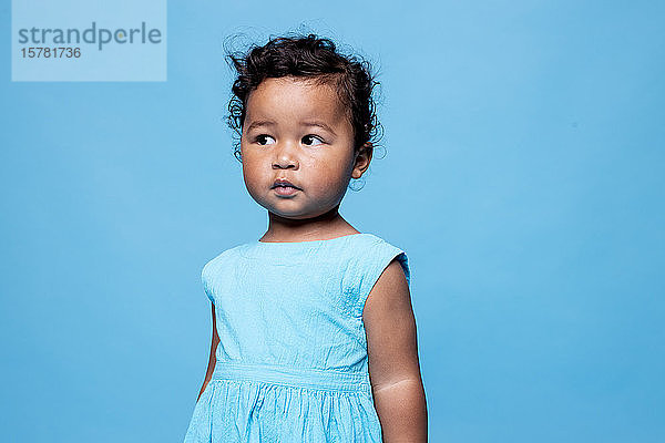 Bildnis eines kleinen Mädchens in hellblauem Kleid vor blauem Hintergrund