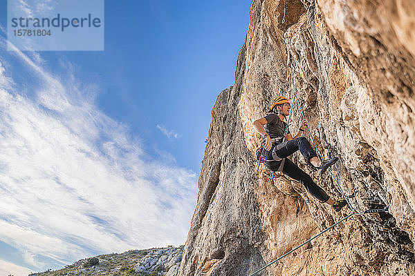 Frau klettert an Felswand