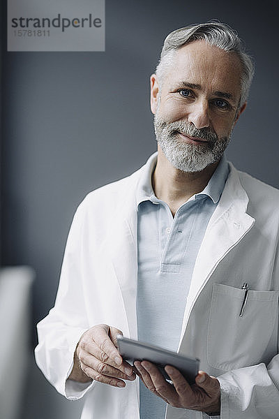 Porträt eines lächelnden Arztes mit digitalem Tablett
