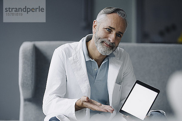 Porträt eines lächelnden Arztes mit digitalem Tablett bei der Konsultation