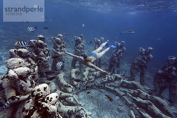 Frau schwimmt in der Nähe einer Unterwasser-Skulptur von Jason deCaires Taylor  Insel Gili Meno  Bali  Indonesien