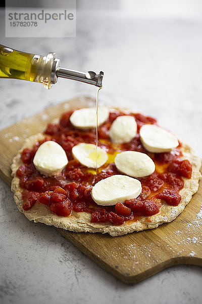 Olivenöl auf halbgemachte Pizza Margharita gegossen