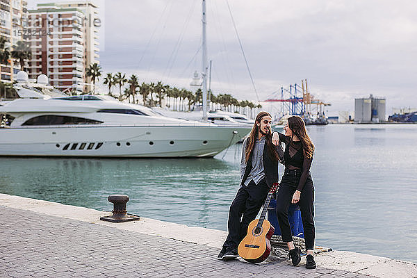 Junges Paar mit einer Gitarre am Hafen