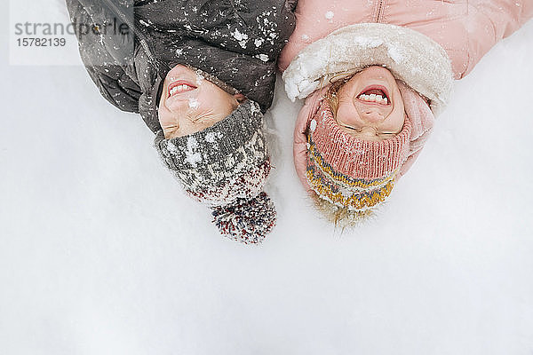 Porträt von zwei Geschwistern auf Schnee liegend