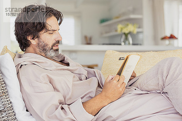 Entspannter Mann im Bademantel beim Lesen eines Buches