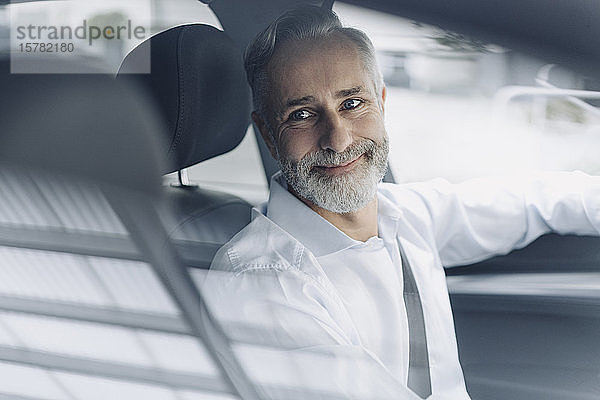 Porträt eines lächelnden reifen Geschäftsmannes in seinem Auto