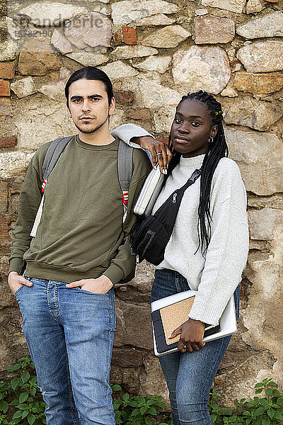 Porträt eines selbstbewussten Paares an einer Steinmauer