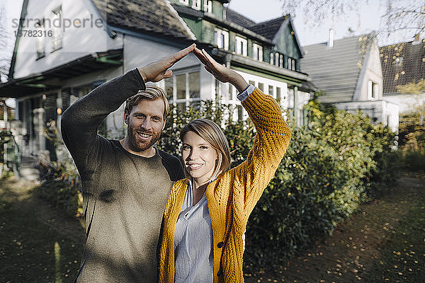 Porträt eines lächelnden Paares  das vor seinem Haus steht