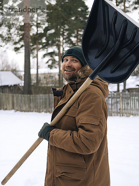 Porträt eines lächelnden Mannes mit Schneeschaufel