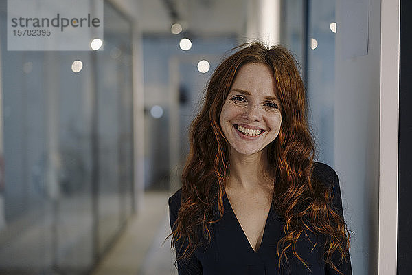 Porträt einer glücklichen rothaarigen Frau in der Büroetage