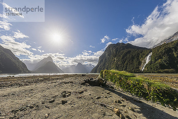 Neuseeland  Sonne scheint bei Ebbe über dem Strand des Milford Sound mit den Bowen Falls im Hintergrund