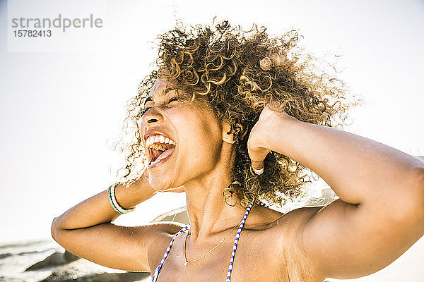 Porträt einer jungen Frau  die am Strand vor Freude schreit