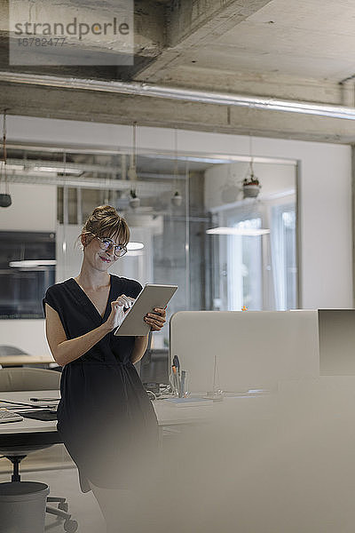 Zuversichtliche Geschäftsfrau benutzt Tablet im Büro