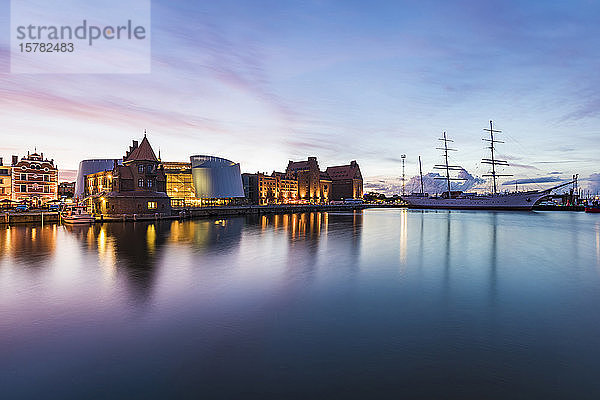 Deutschland  Mecklenburg-Vorpommern  Stralsund  Uferpromenade der Küstenstadt in der Abenddämmerung mit Segelschiff und Ozeaneum im Hintergrund