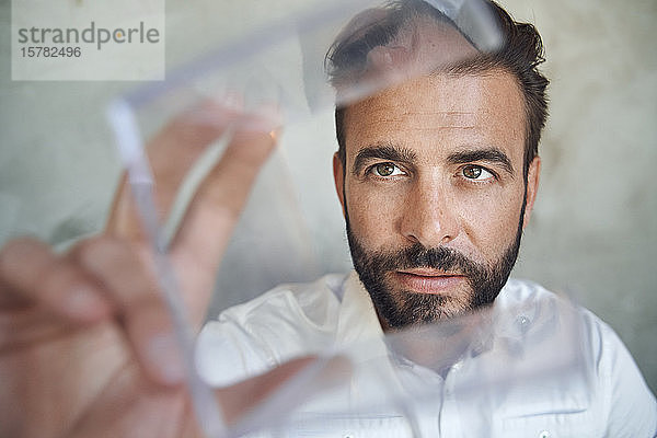 Porträt eines Geschäftsmannes  der einen transparenten Würfel betrachtet